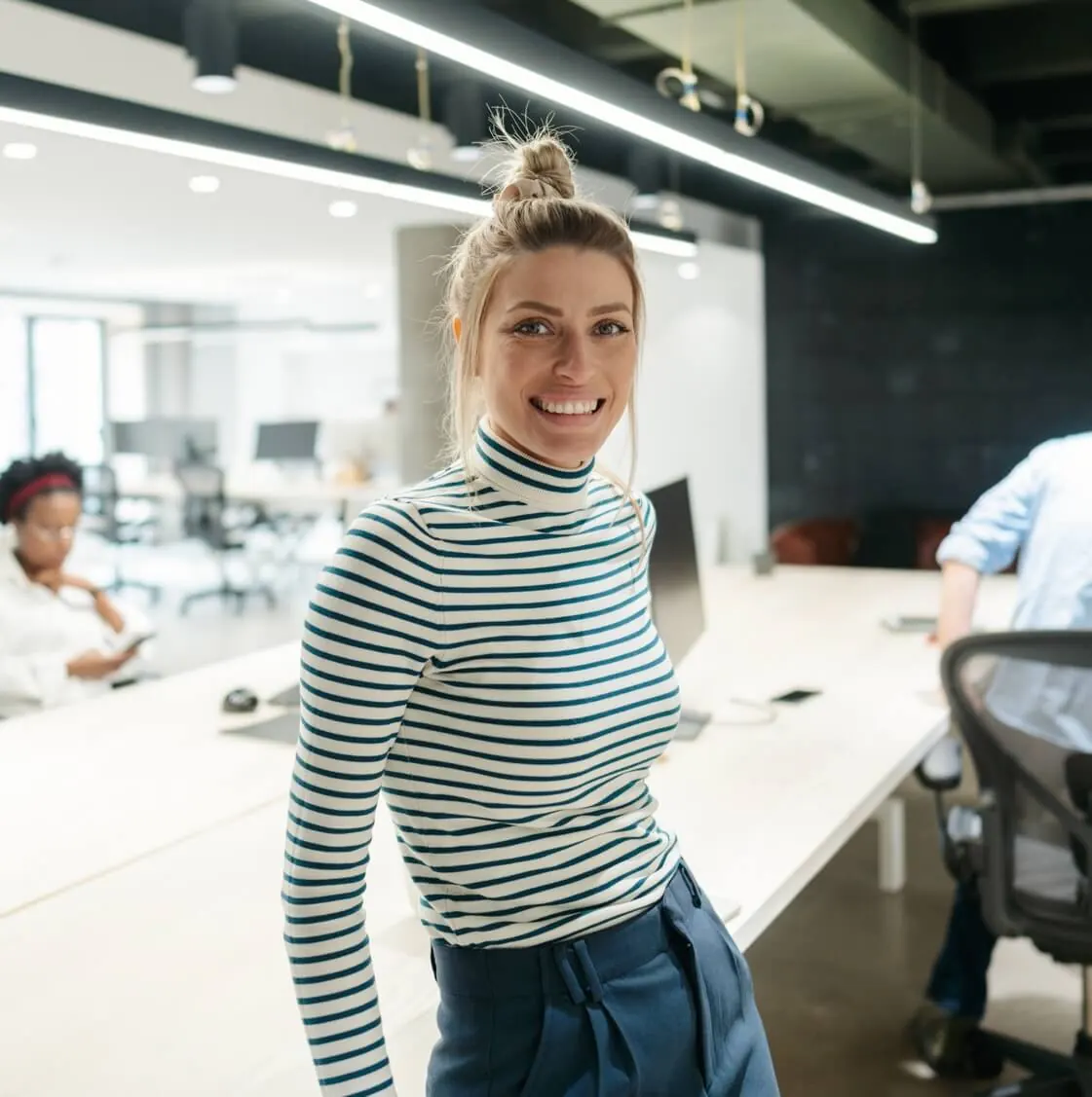 A woman standing in front of a desk in an office.