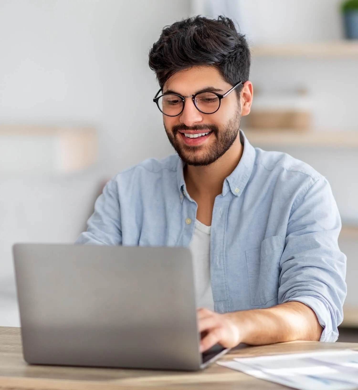 A man sitting at a table using a laptop computer.