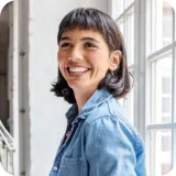 A woman smiling in front of a window.