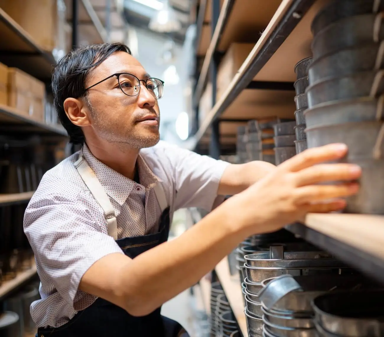 A man is looking at a shelf full of pots.